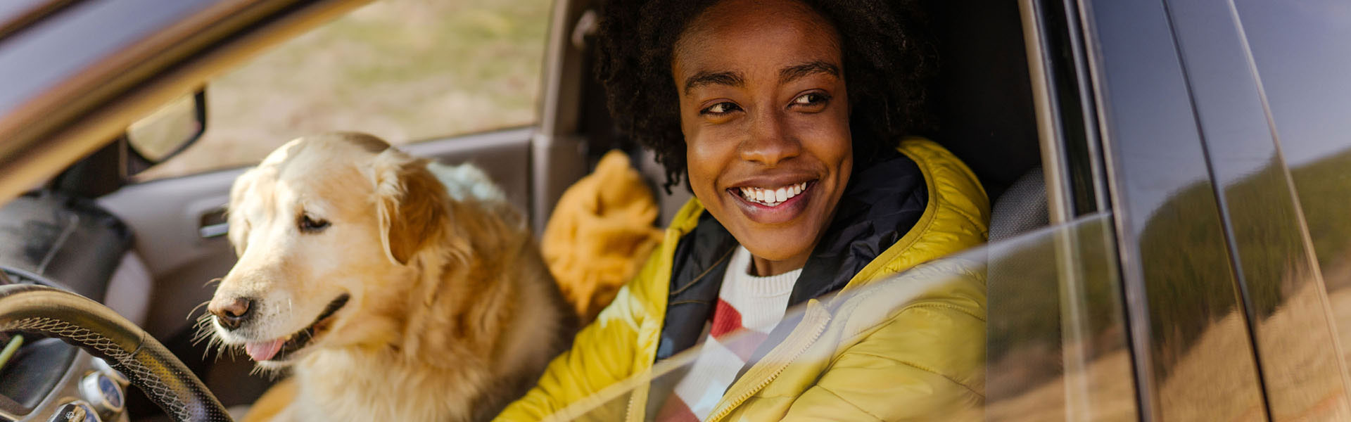 A young woman and a dog are in a car.	