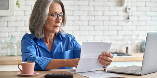 An older woman is looking at statements at her work station.