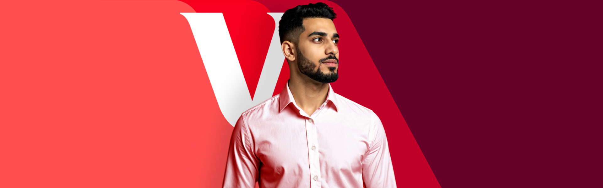 A man in a light pink button-down looks off to his left confidently. He stands in front of a red background featuring the signature Vanguard "V