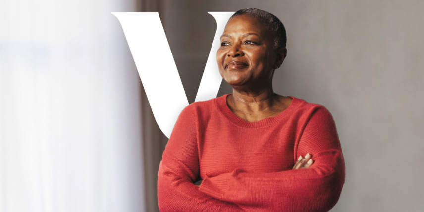 A woman wearing a red sweating and standing confidently with arms crossed