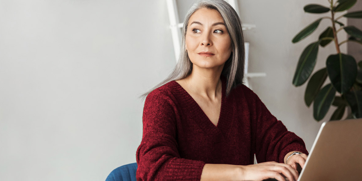 Photo of gray-haired businesswoman typing on a laptop