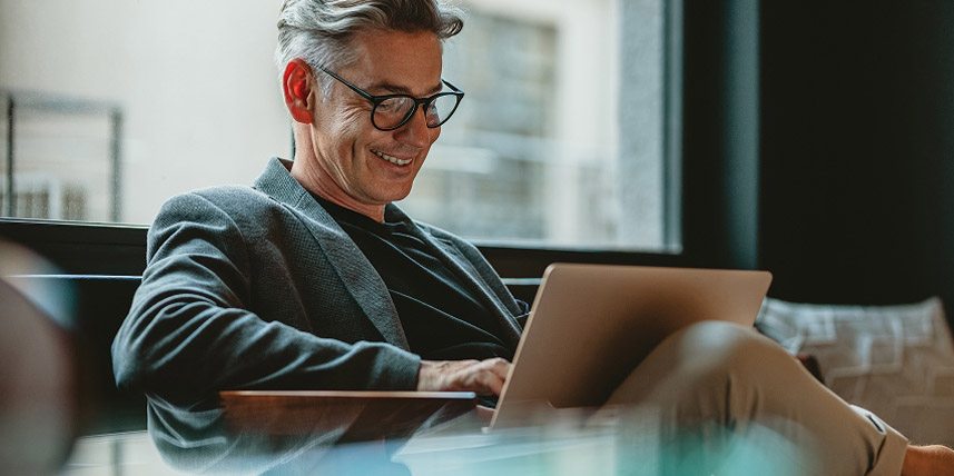 A man sitting in on a couch using his laptop.