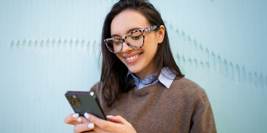 Woman with glasses looking at a mobile phone.