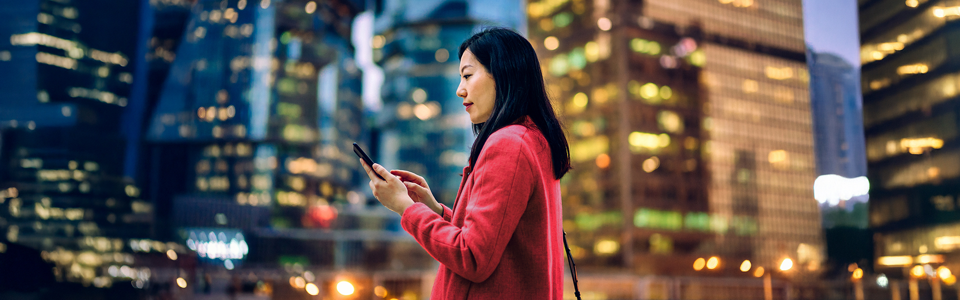 A woman uses a mobile phone in an urban setting.