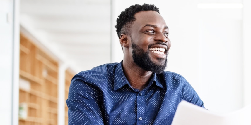 Man smiling widely while holding papers and looking to the side