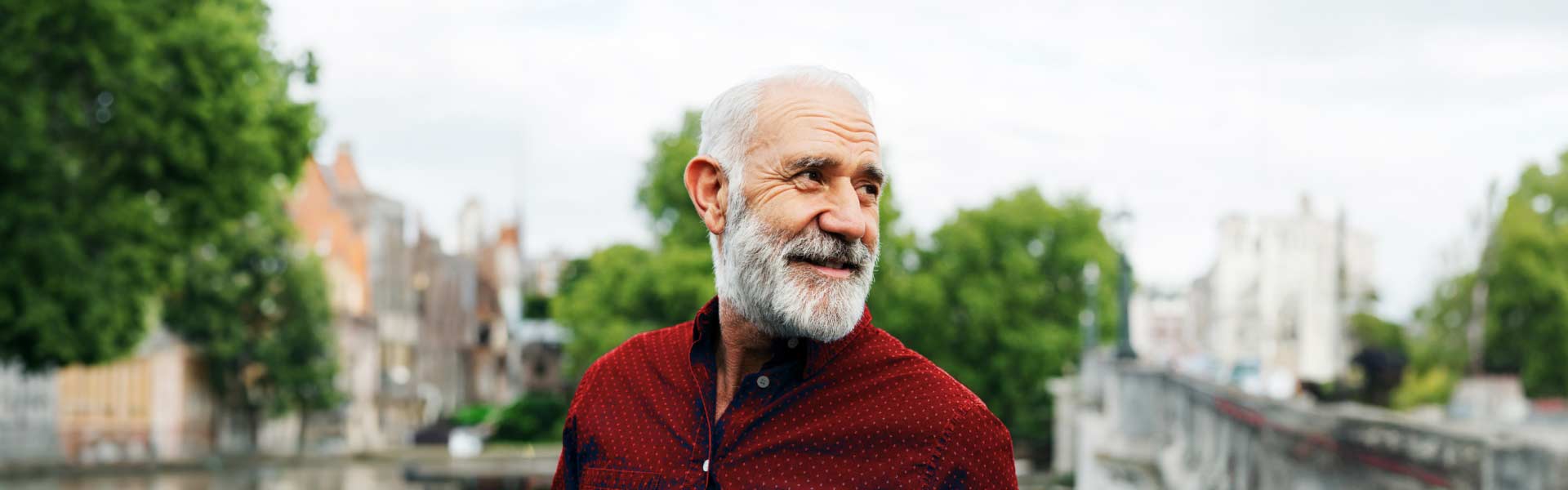 Older man standing outside wearing a red button-down shirt