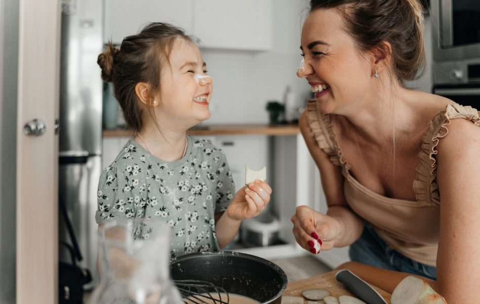 Woman smiling with her daughter while baking.