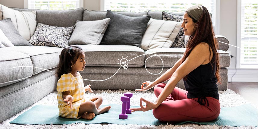 A mother and daughter meditate together on their living room floor.