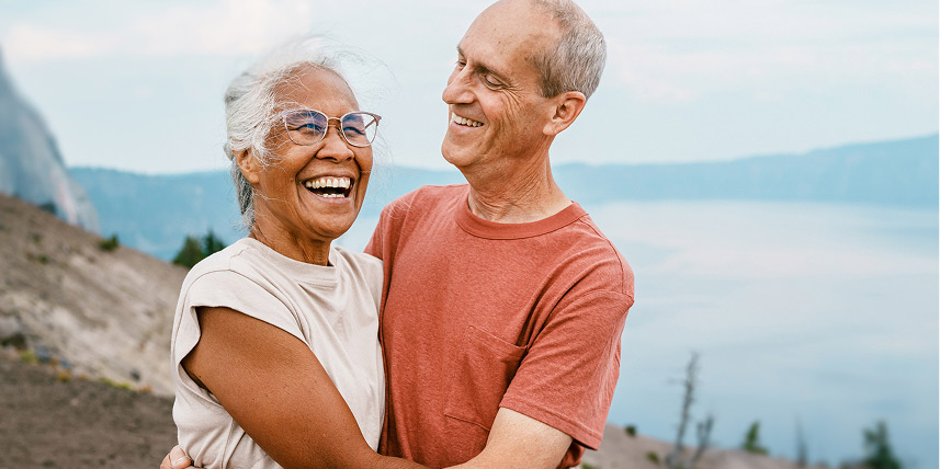 Happy senior couple embrace on mountain trail.