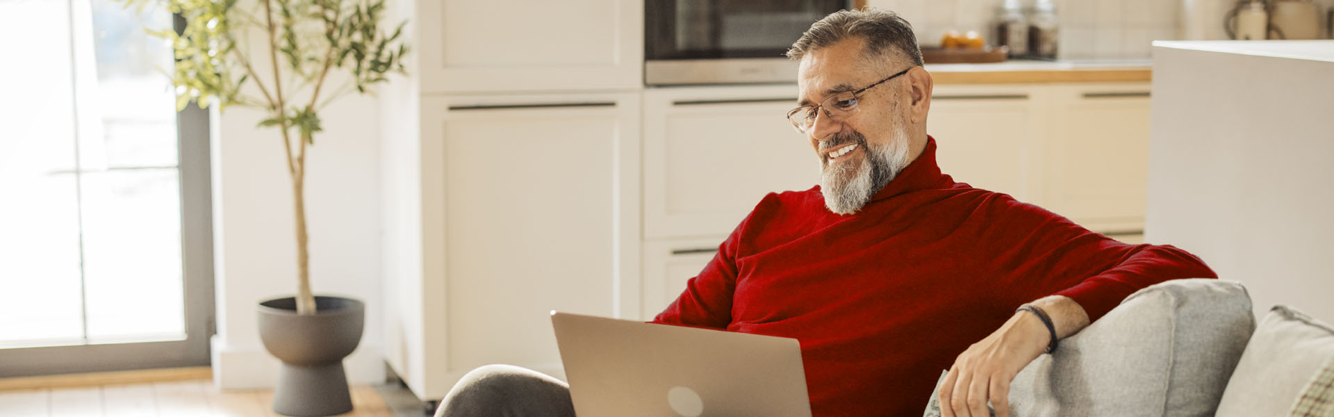 A middle-aged man is looking at his laptop in his living room