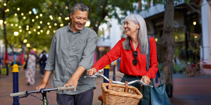 A middle-aged couple pushing their bikes through a downtown square