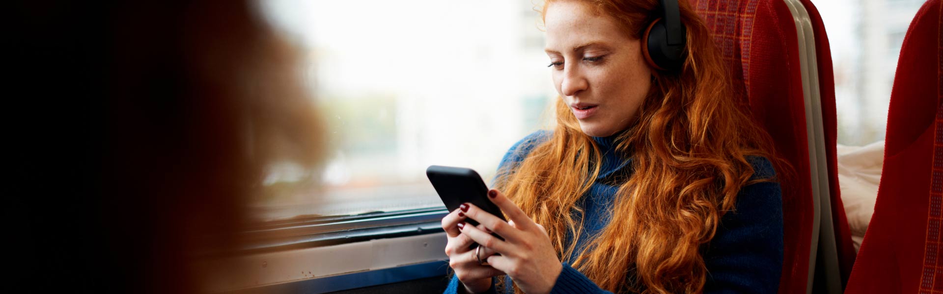 Woman with red hair using phone while riding a train