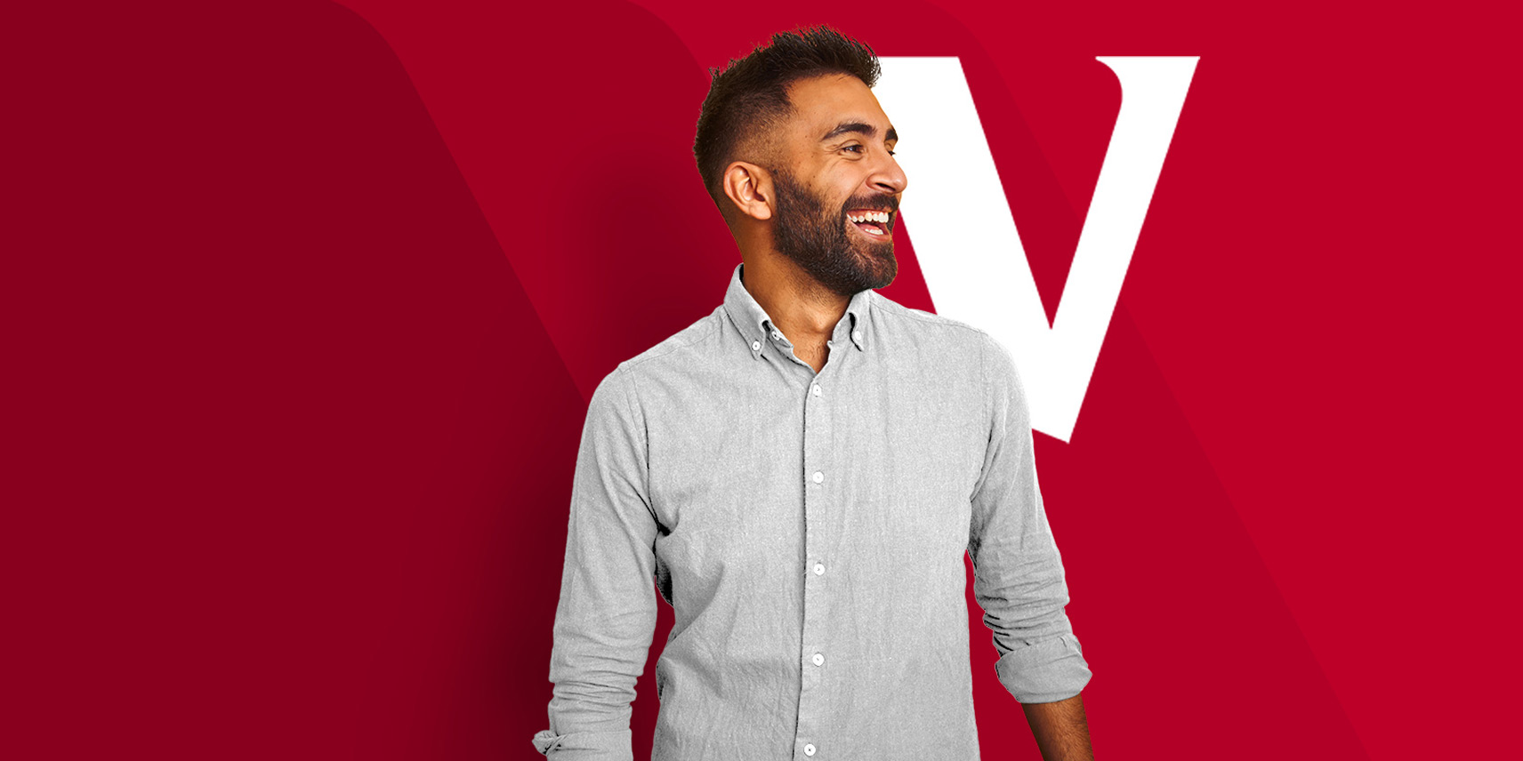 A man looking into the distance smiles as he stands in front of a red background displaying the Vanguard V logo.
