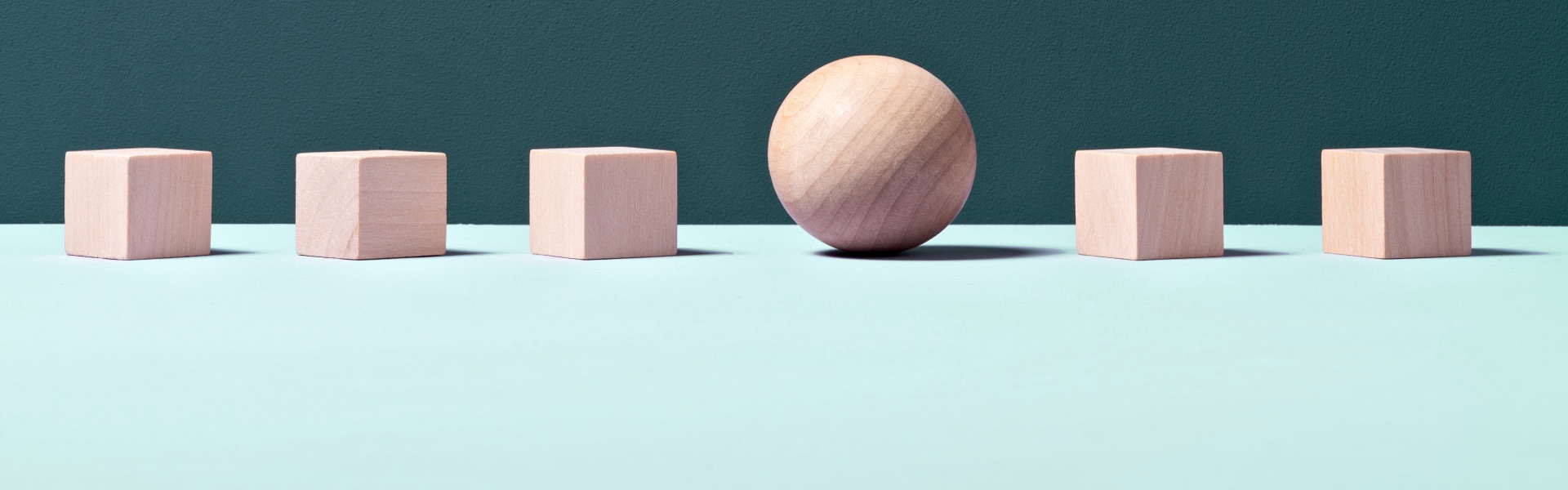 A wooden sphere sits between 3 wooden cubes.