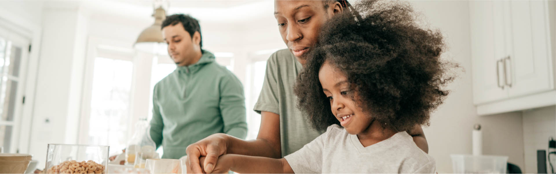 Two adults and a child in the kitchen cooking.