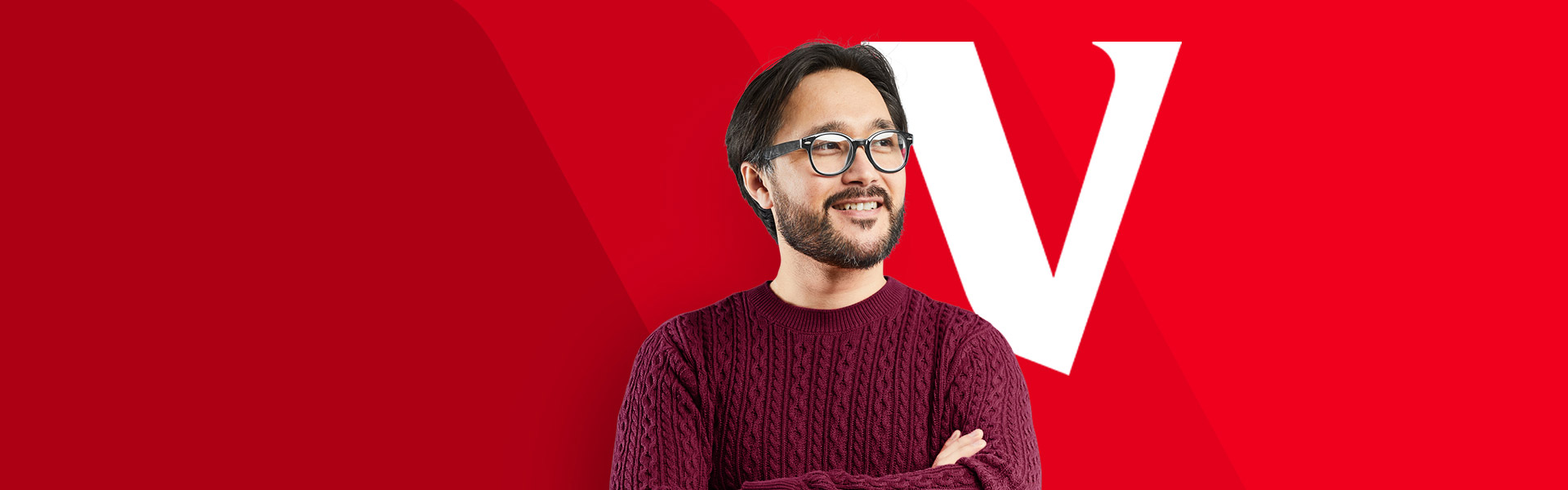 Smiling person with glasses in front of a red background with a white "V"