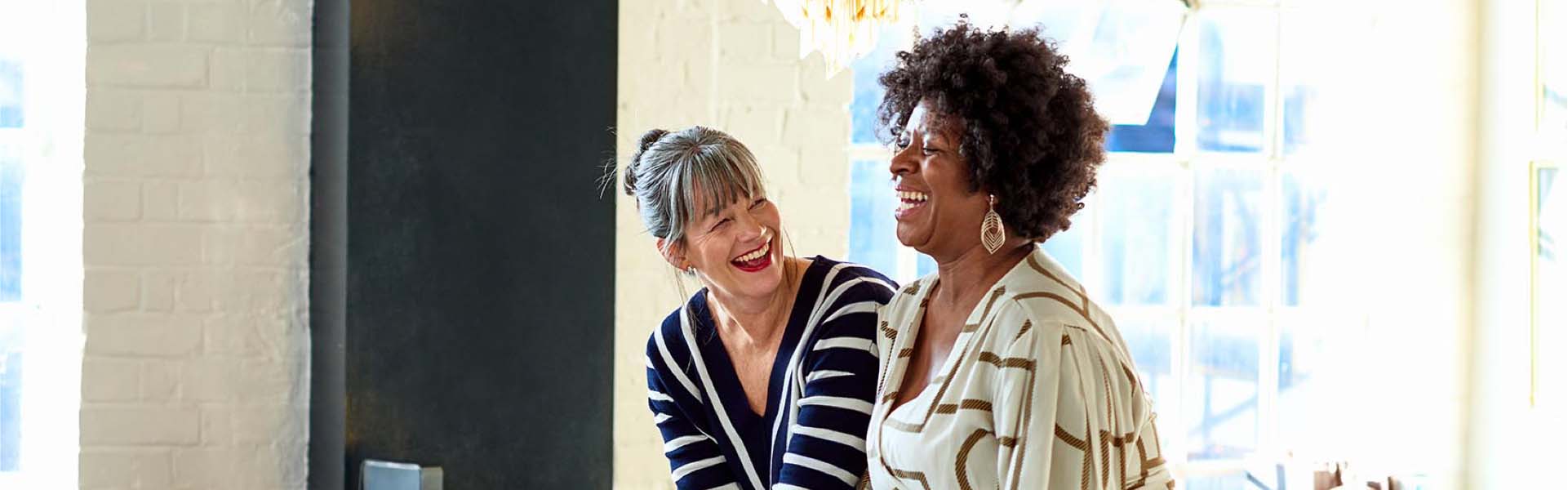Mature women laughing together in stylish loft apartment