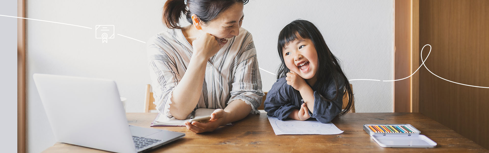 Little girl and mom smiling while doing homework together at the table.