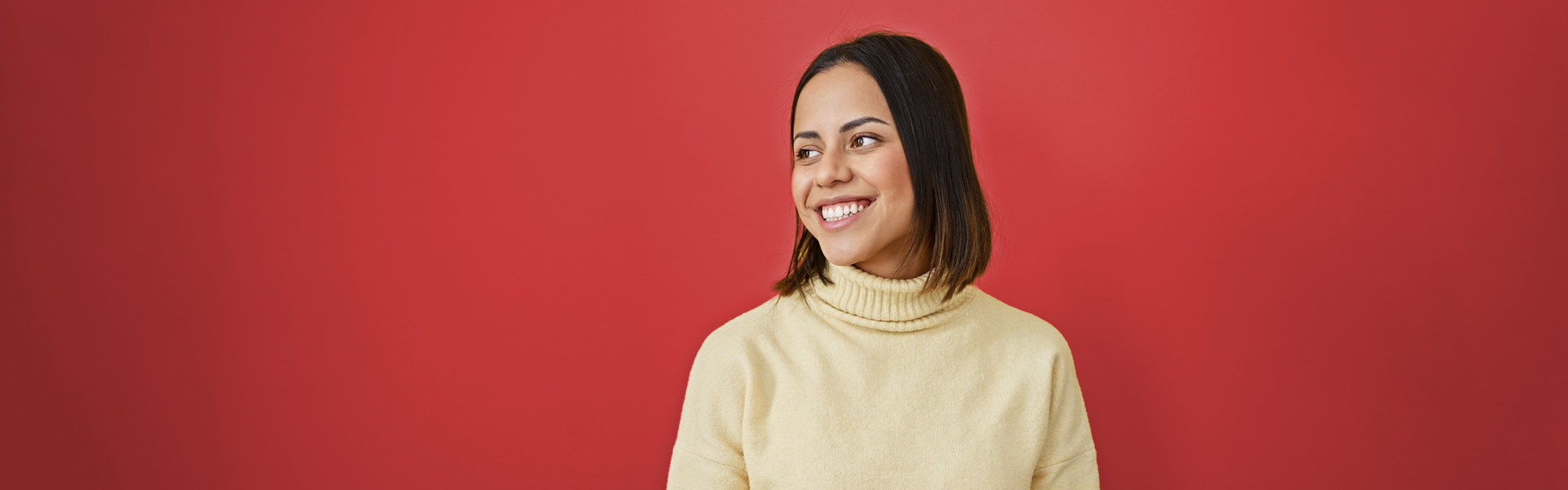 A young woman with long dark brown hair smiles off to the side. She is wearing a cream turtleneck sweater. The background is a solid red.