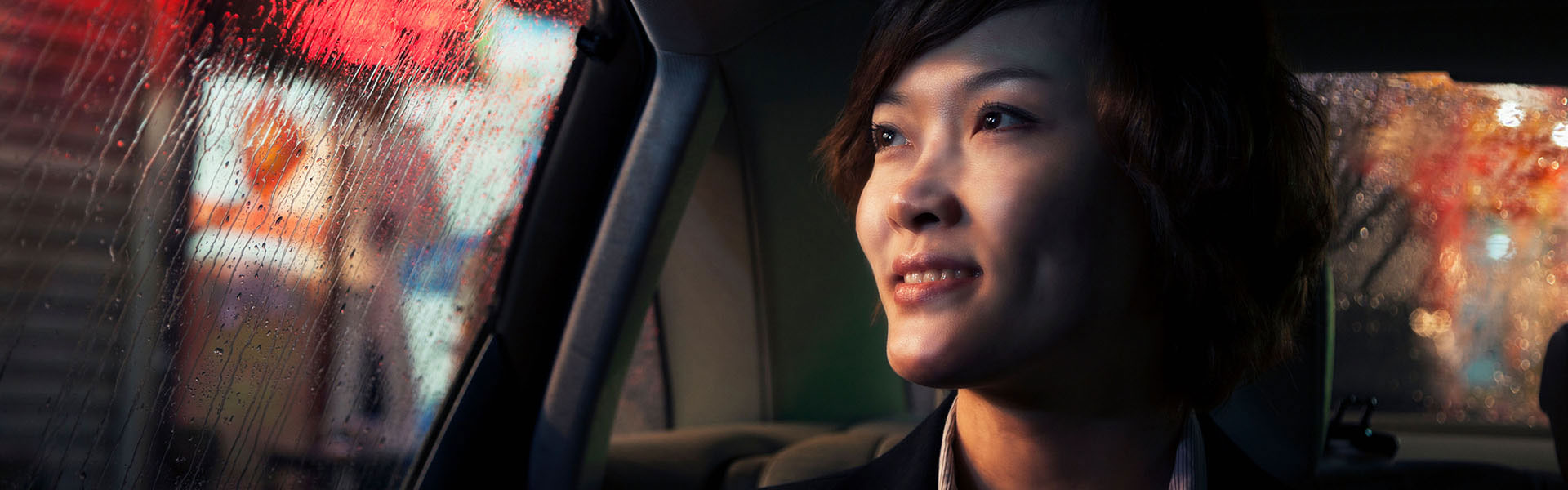 A young woman is smiling out a car window.	