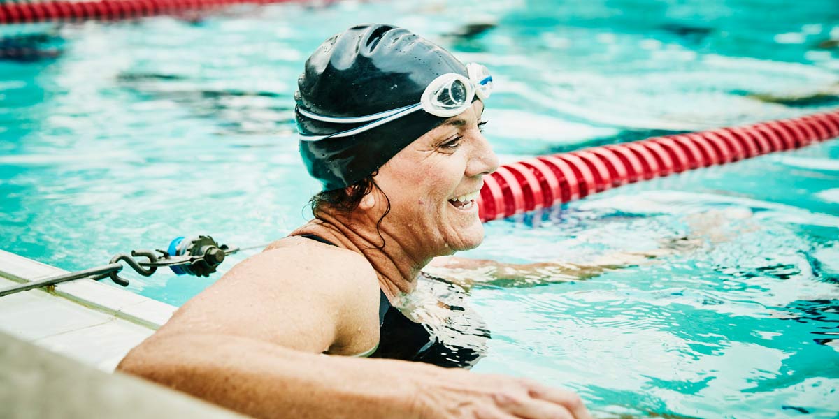 A woman in a pool rests in between swimming laps.