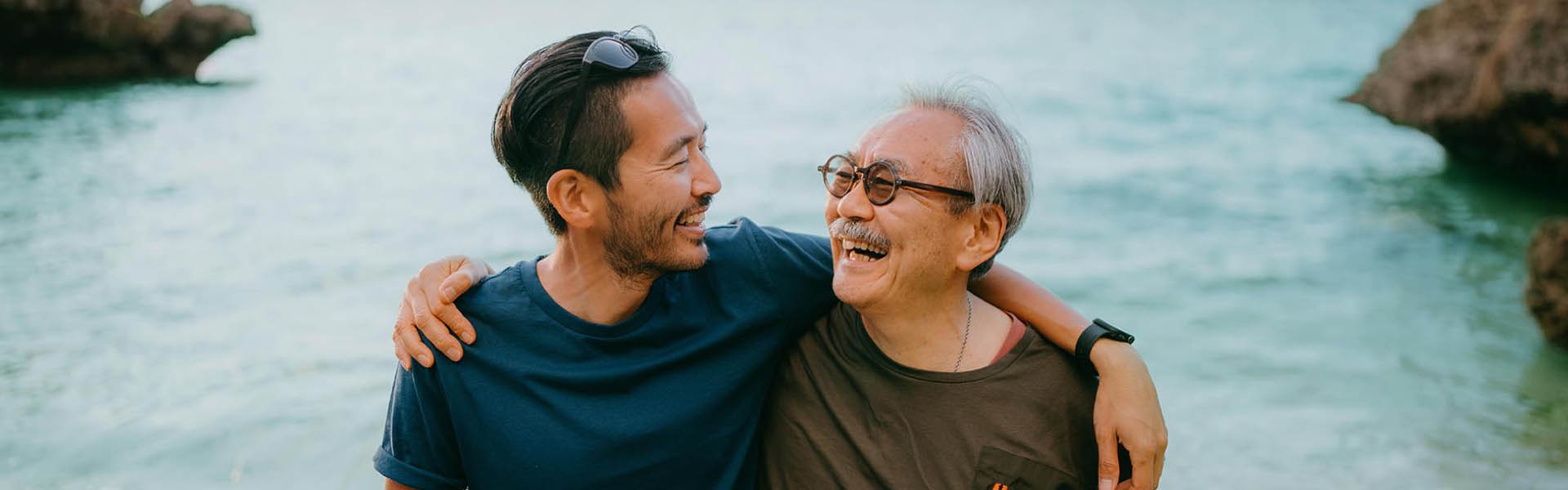 Senior Father and adult son having a good time at the beach at sunset.