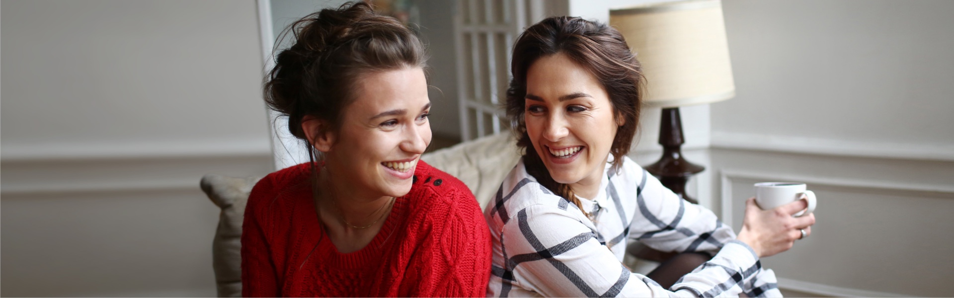 Two people sitting back-to-back while turning around to smile at one another. 