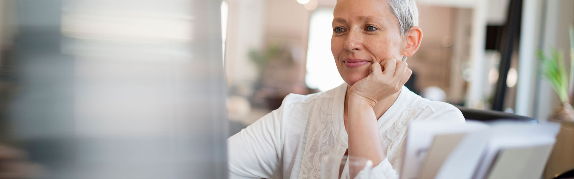 An older woman is staring at something in front of her while resting her chin on her hand.