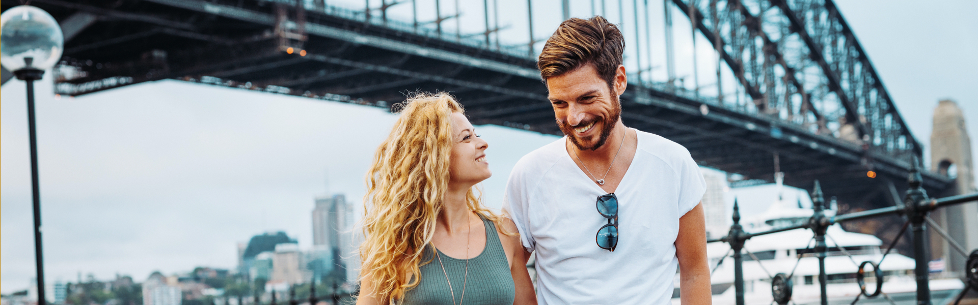 A smiling couple by a bridge.