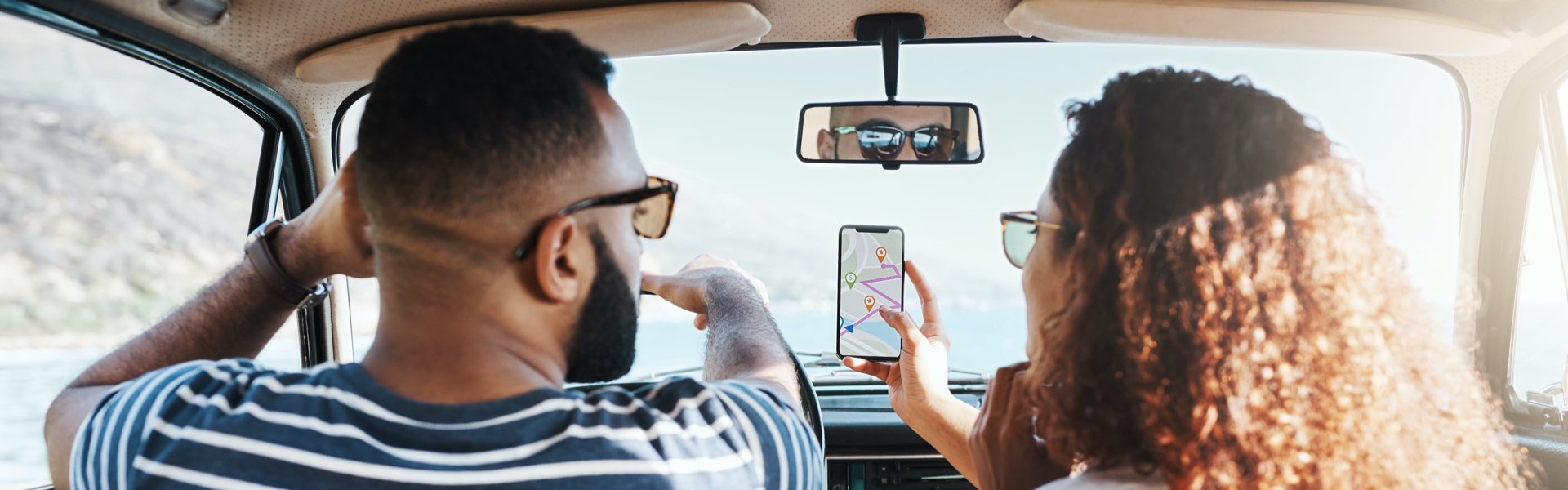 A car passenger is sharing a GPS route on her smartphone with the driver.