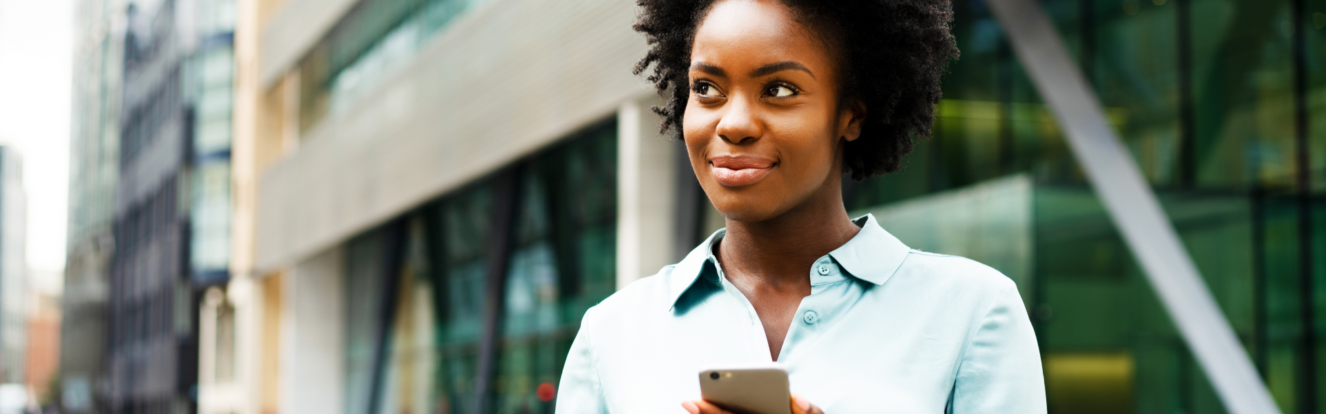 Woman, with a smile on her face, stares up from smartphone. 