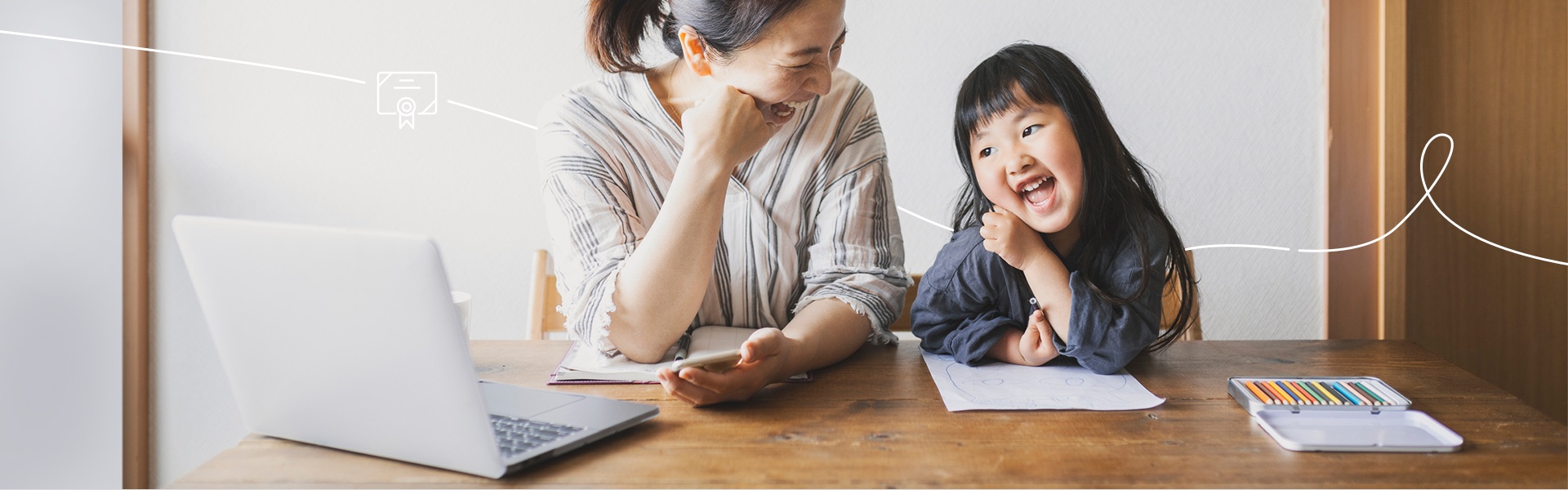 Little Girl and mom smiling while doing homework together at the table