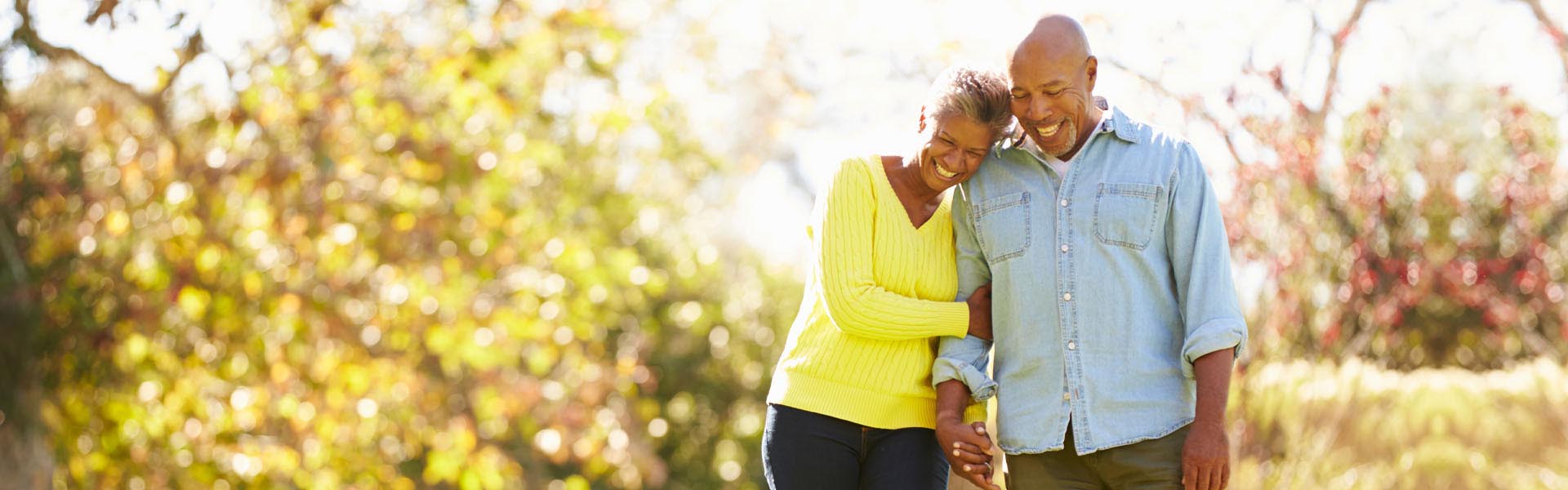 Senior couple walking through autumn woodland