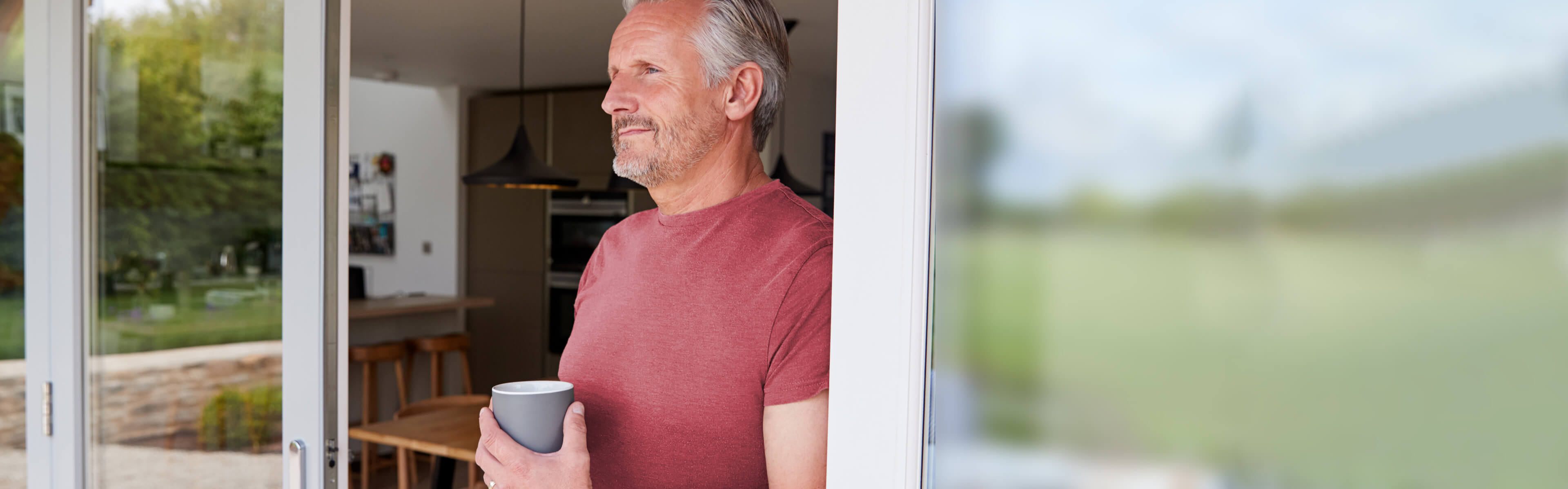 Man holding cup looking outside