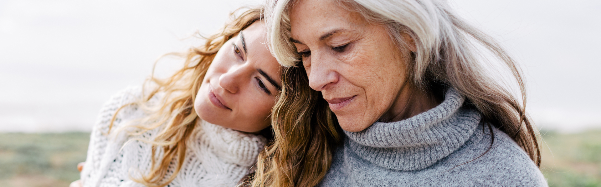 A young woman is leaning her head on an older woman’s shoulder.