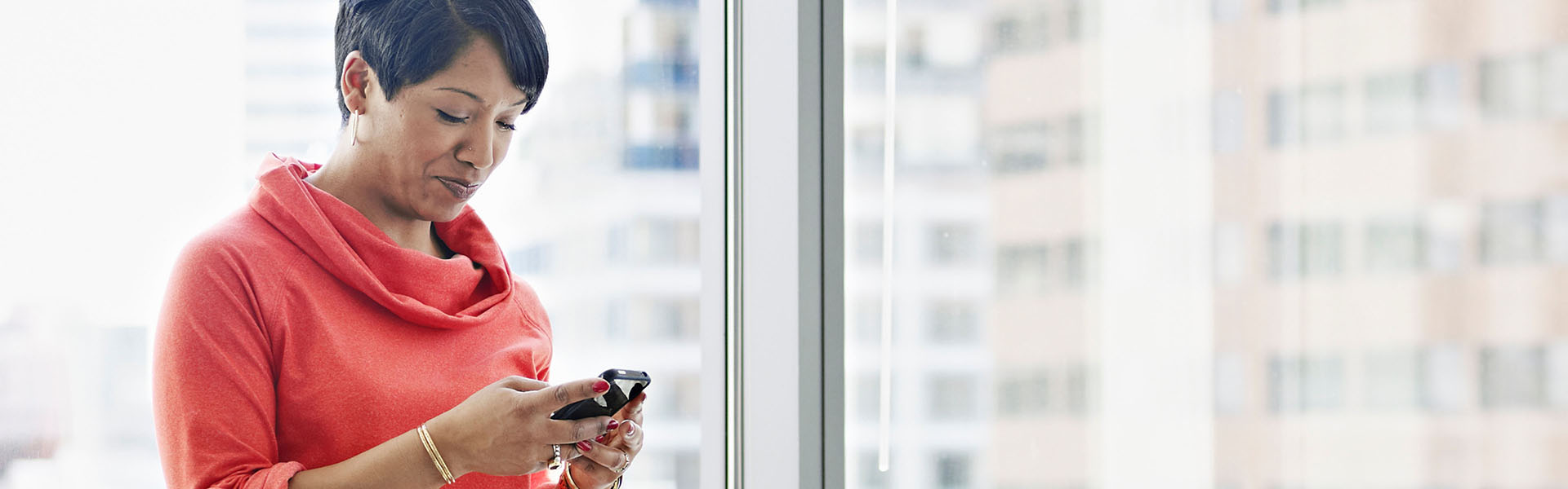 A woman is looking down at her smartphone.