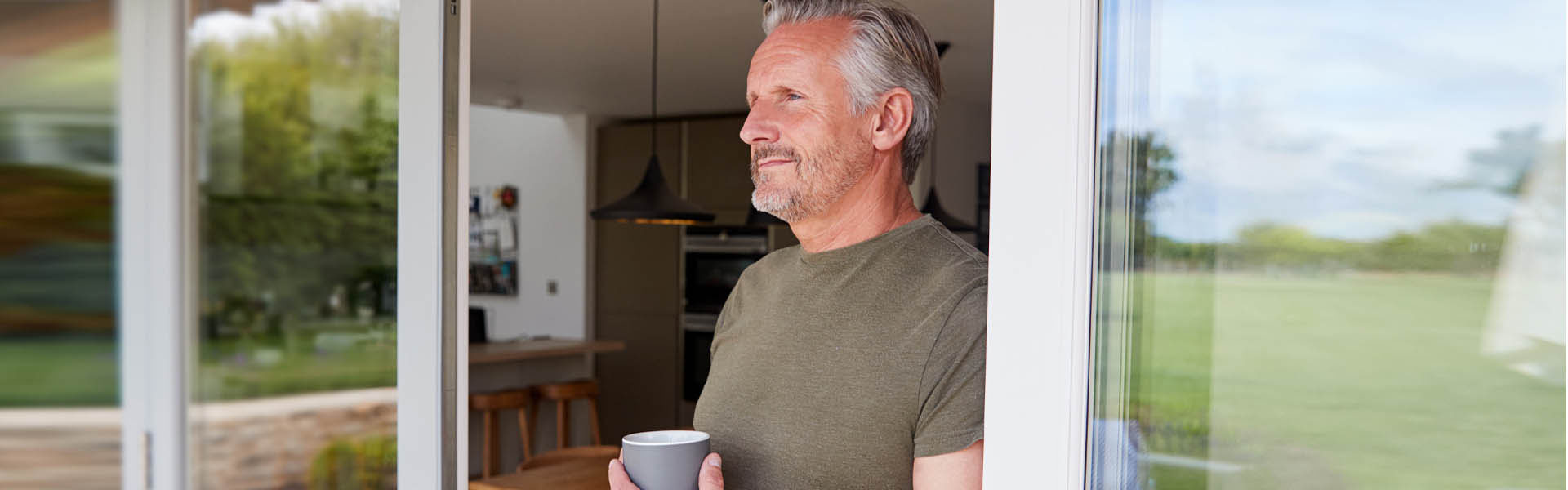 An older gentleman looking out his back door, smiling contentedly. 