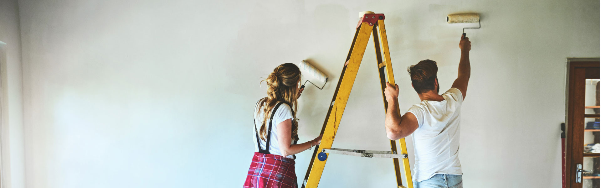 Man and woman paint a wall. 