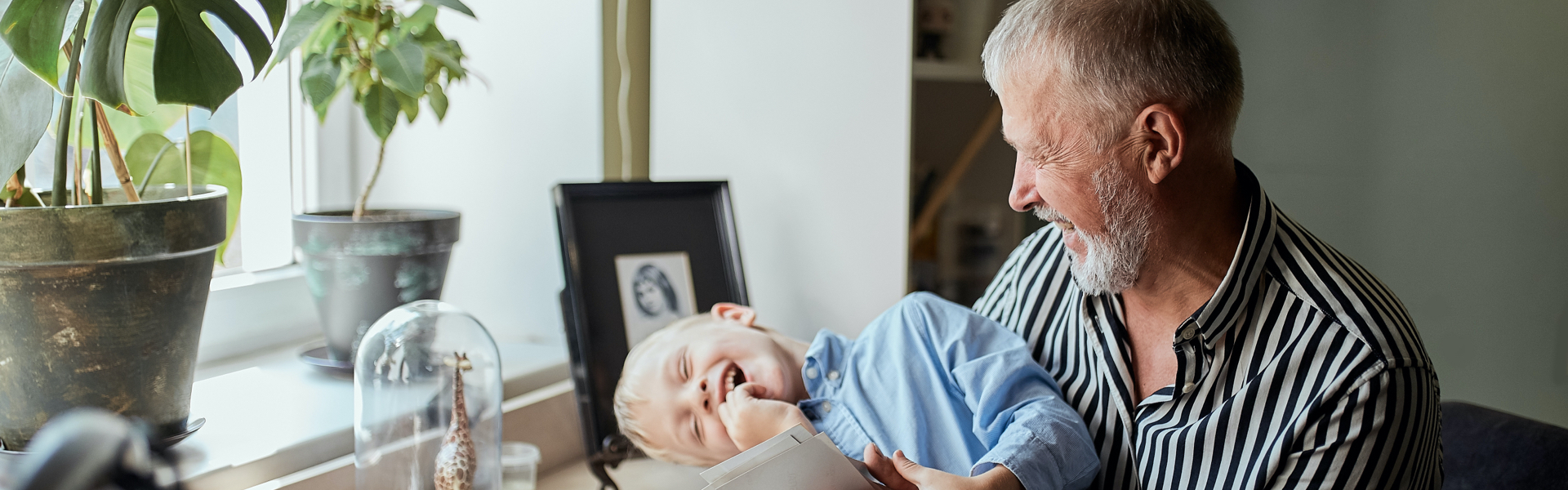 An older man is holding a laughing child.