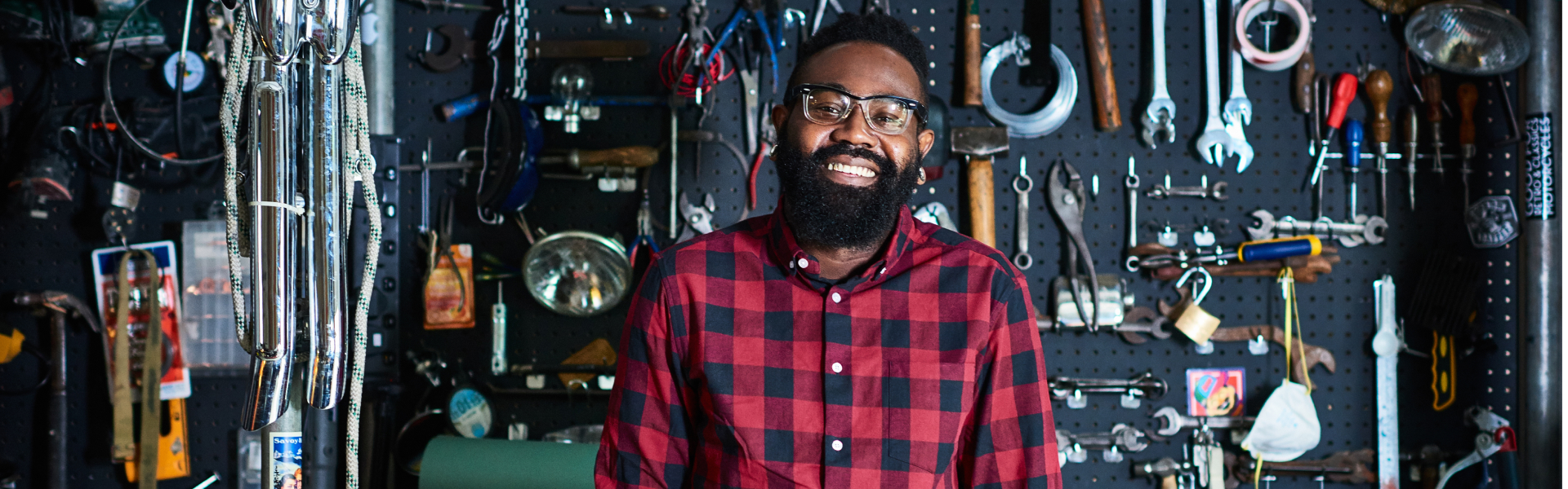 A man in a tool shed is smiling at the camera.