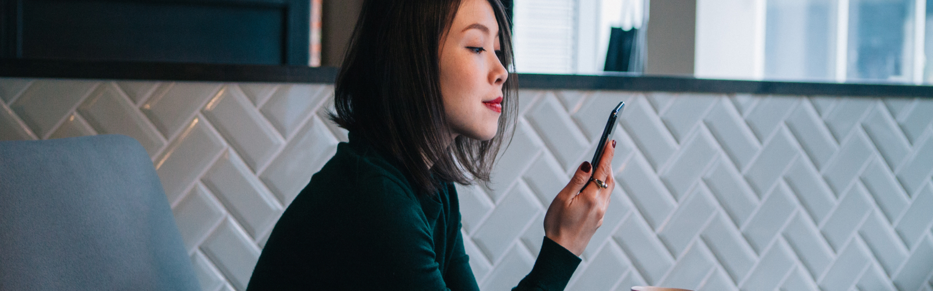 Young woman smiles while looking at smartphone. 