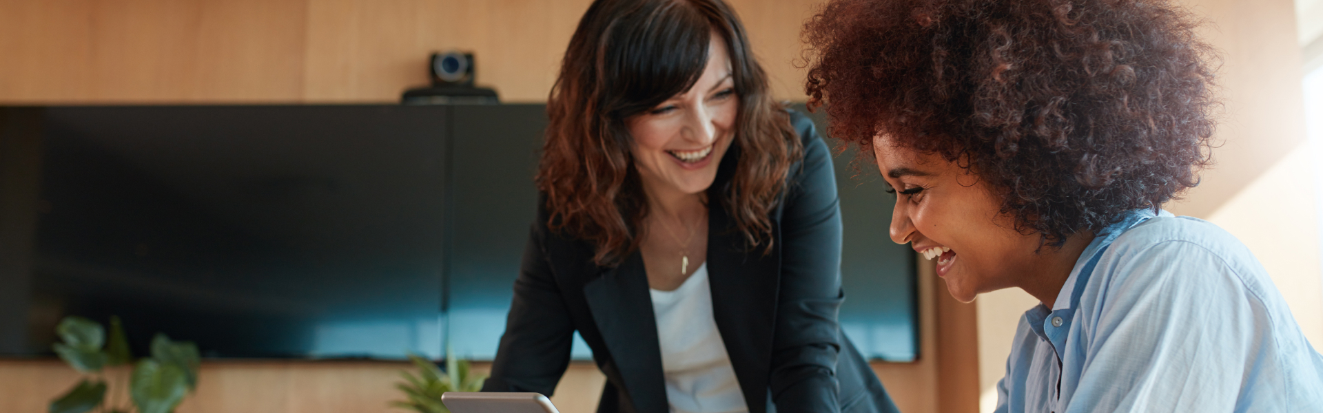 Two young women are laughing at something out of the frame.