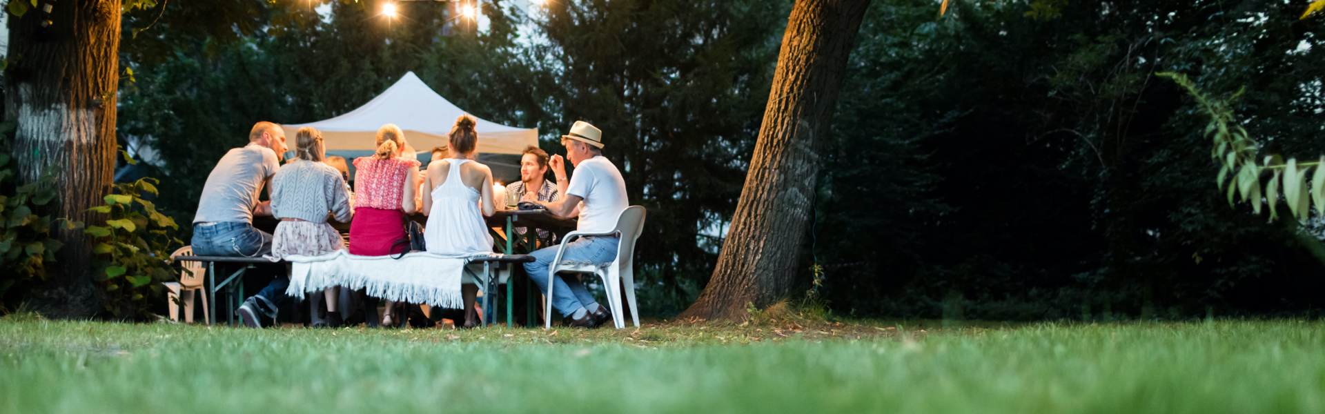 A group of people are gathered around and eating on a table outside.