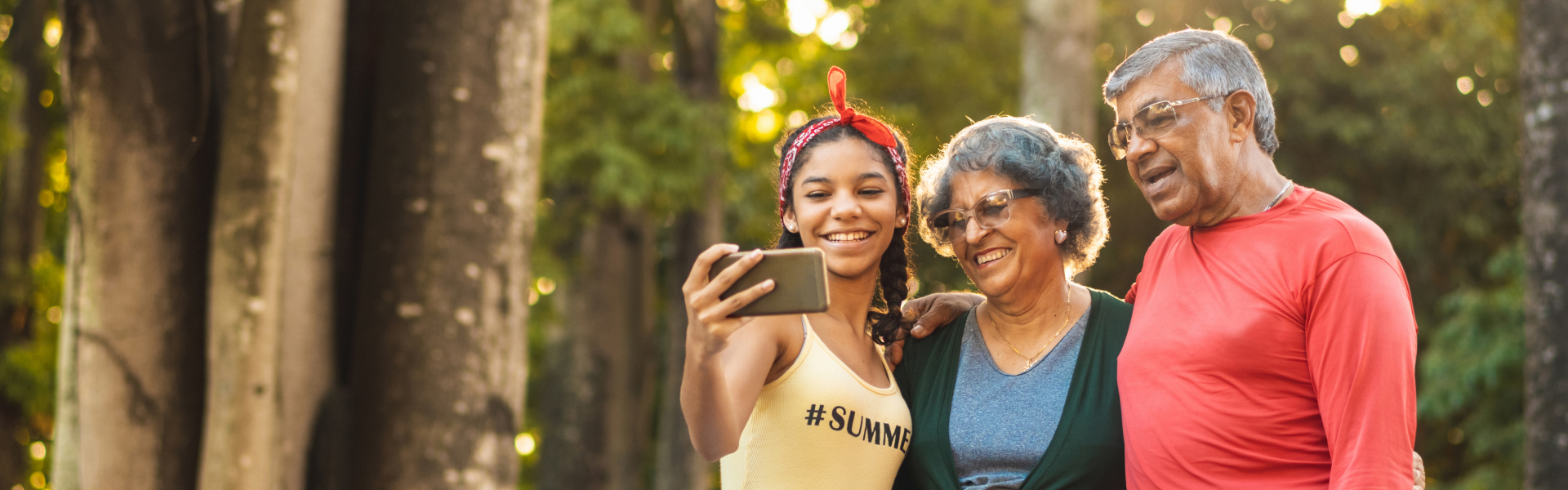 Three people are smiling while looking at a smartphone.