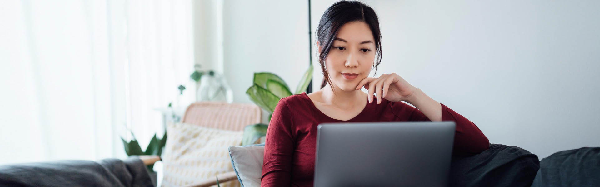 Female sitting on the sofa with her laptop on her lap. 