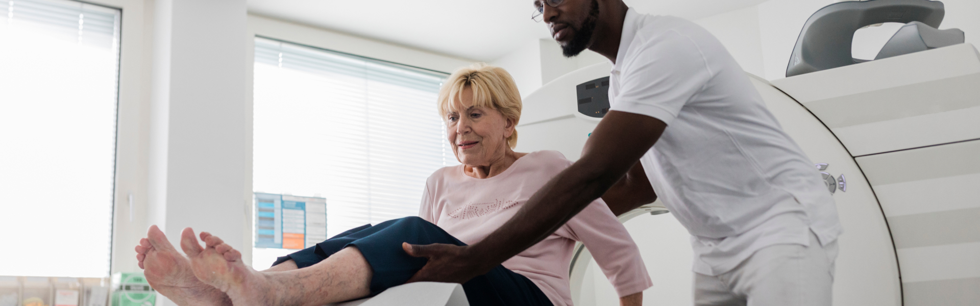 A young man is helping an older woman sit down.