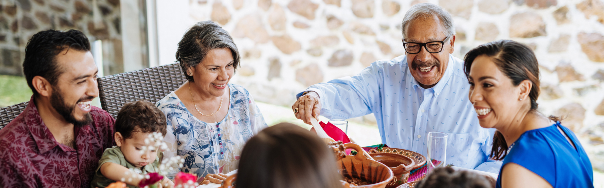 A group of people are smiling while sitting at a dining table.