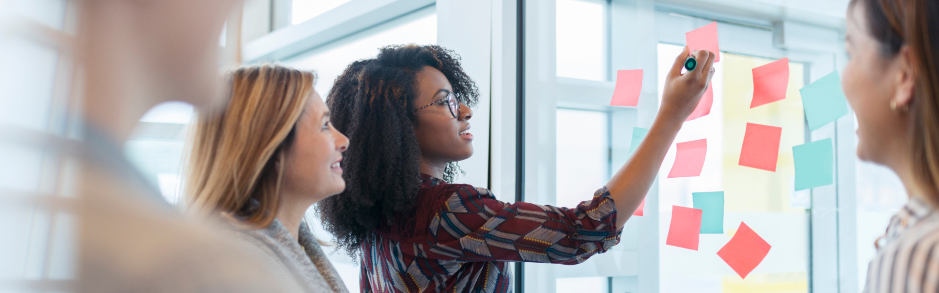 A young woman is writing on a sticky note.