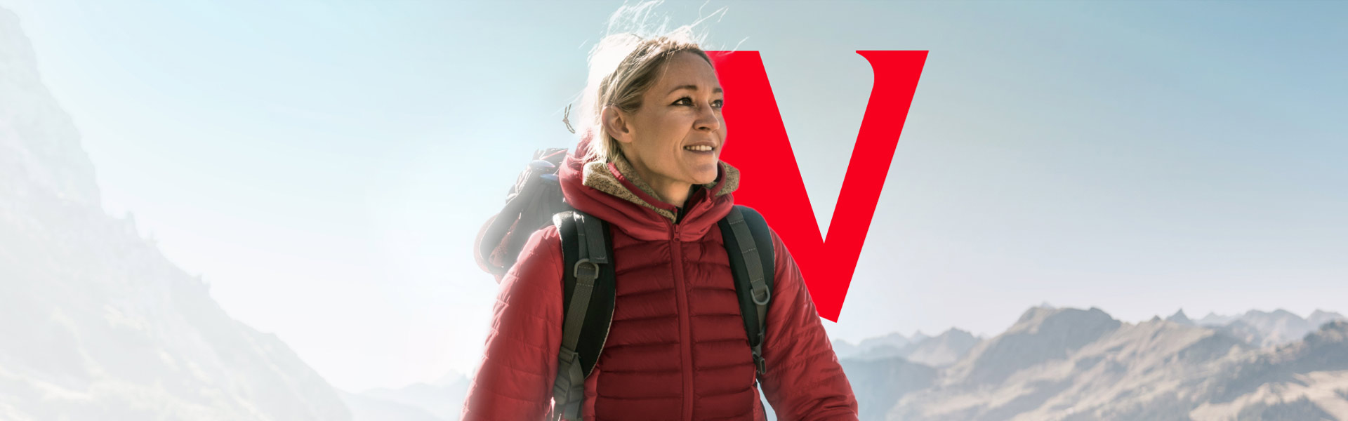 A woman outside hiking on a mountain and smiling.