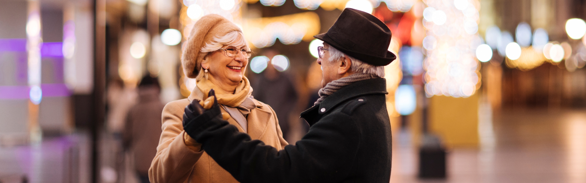 An older man is holding an older woman’s hand.